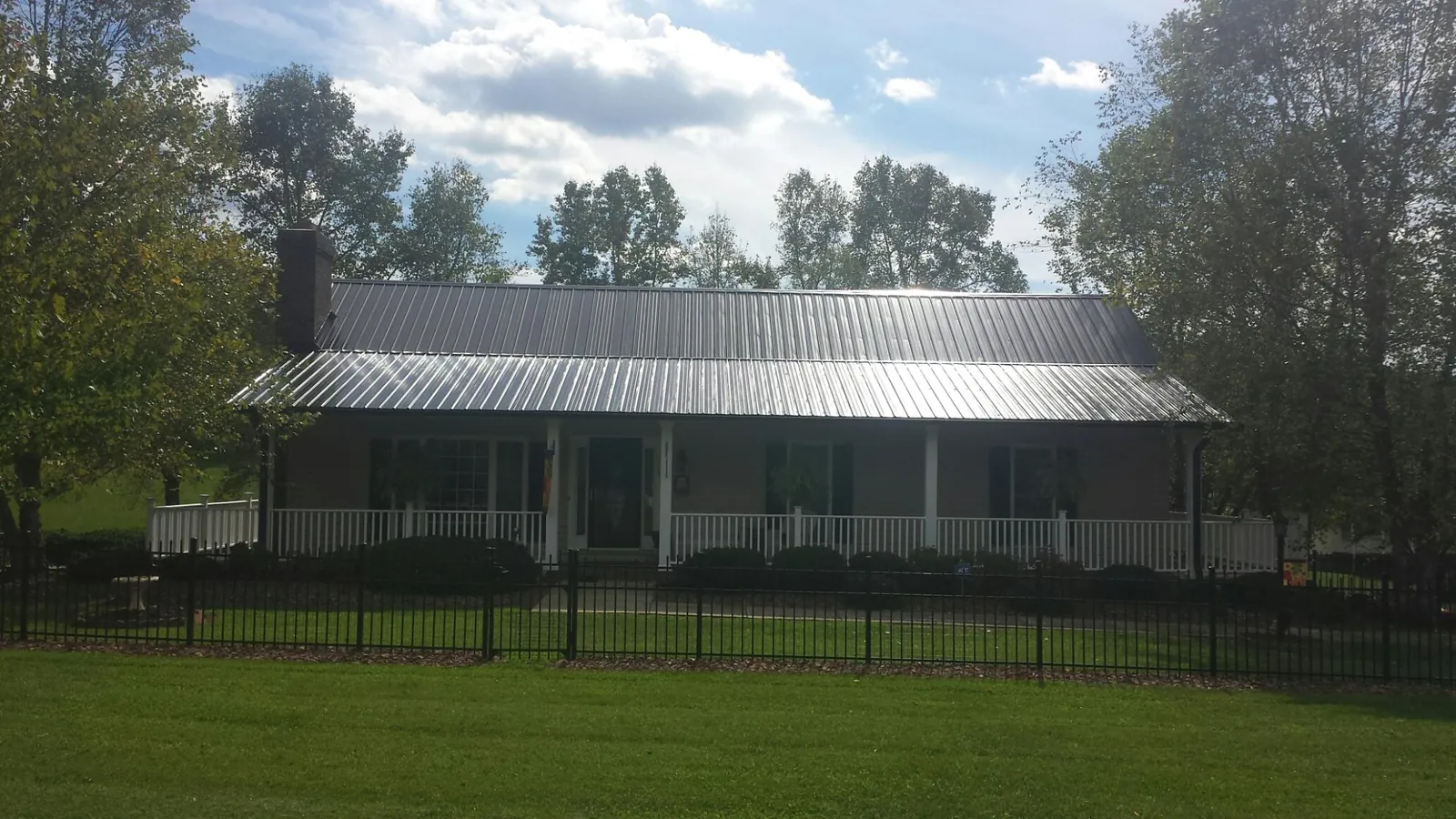 Gray metal roof on a brick ranch with a full width front porch — Gutter Guard Installation work by our crew in Worthington